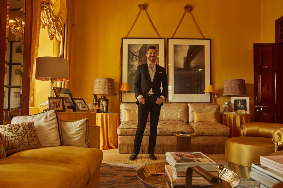 Cormac Lynch in his sumptuous drawing room. The curtains are made from silk from Benares and he had the fabric on the sofas dyed to match. The table in the foreground is actually a thali tray, he uses these trays  a lot as tables. The two large prints over the sofa depict the Brooklyn Bridge and the Flatiron Building in New York. Photo: Yoshi Studio