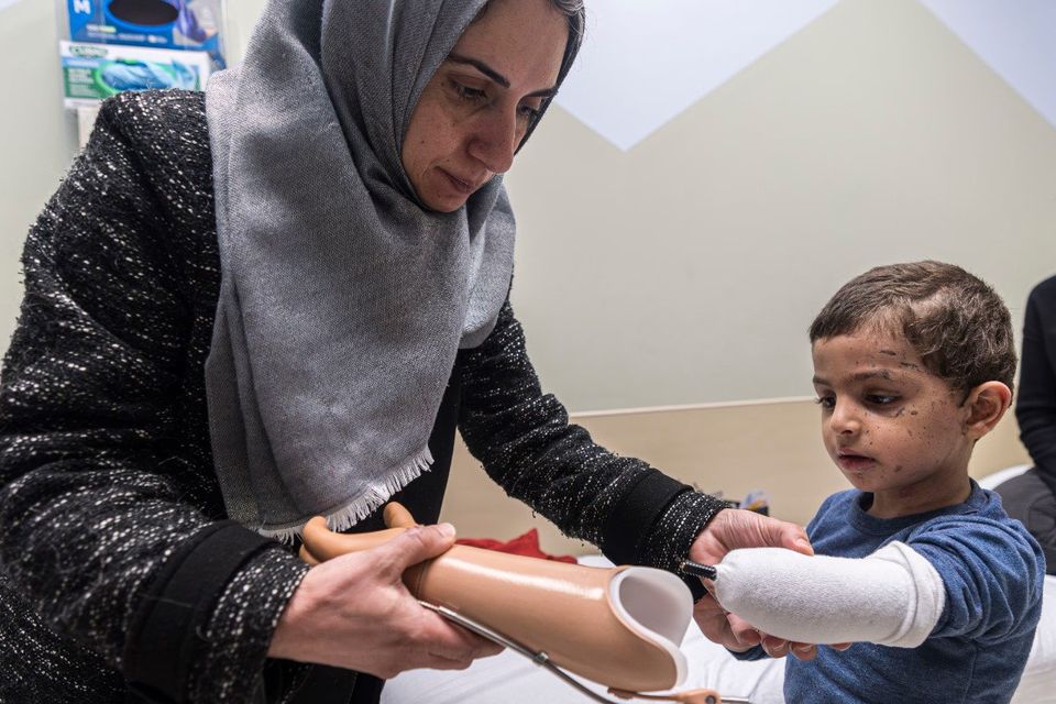 Maha Abu Kuwaik helps her nephew Omar Abu Kuwaik (4) attach his new prosthetic arm at Shriners Children’s Hospital in Philadelphia. Photo: AP