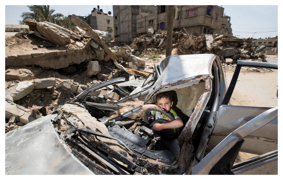 A boy plays in a wrecked car in Gaza