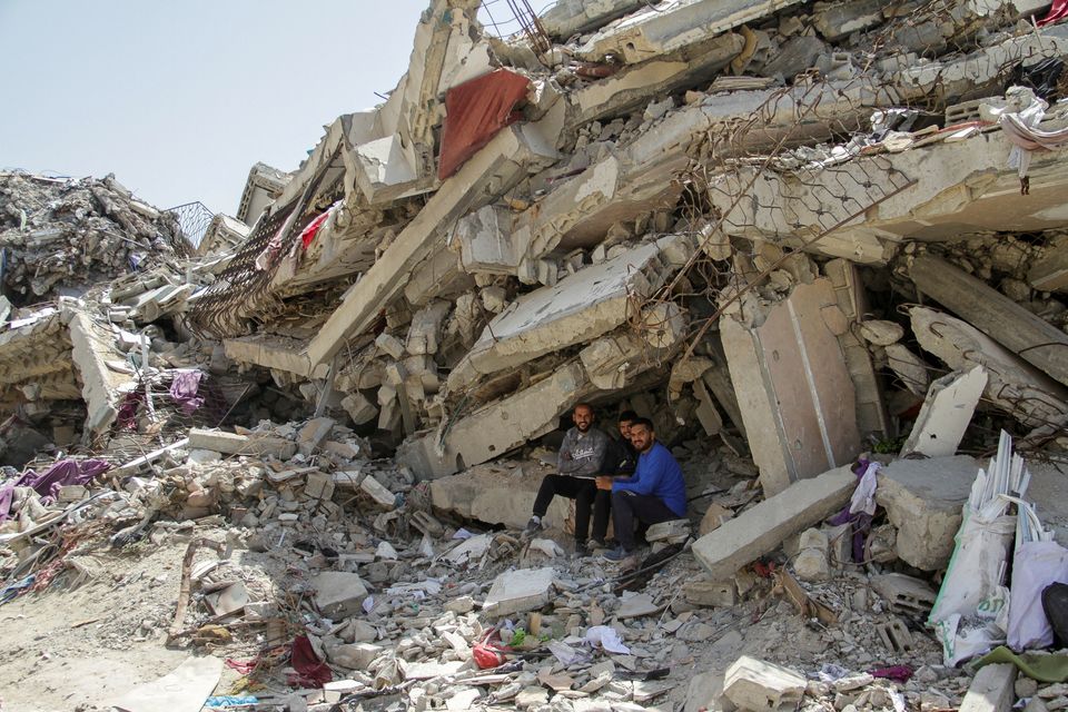 Palestinians sit at the rubble of a residential building destroyed by Israeli strikes in the northern Gaza Strip. Photo: Reuters