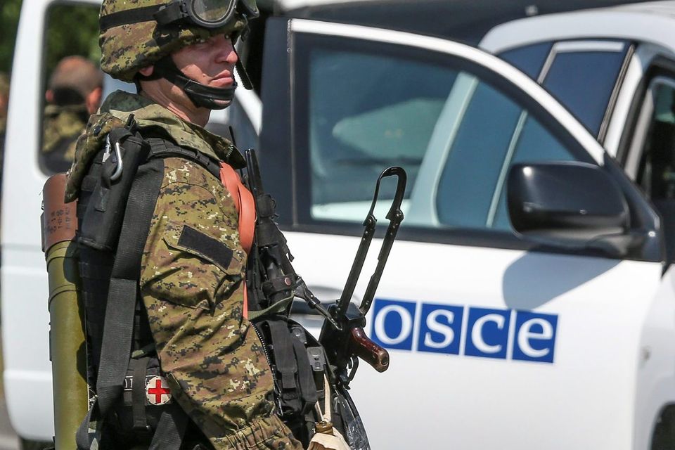 An armed pro-Russian separatist looks back next to a vehicle of the OSCE's monitoring mission in Ukraine, on the way to the site in eastern Ukraine where the downed Malaysia Airlines flight MH17 crashed, outside Donetsk