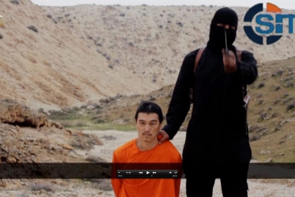 A masked, black-clad militant, who has been identified by the Washington Post newspaper as a Briton named Mohammed Emwazi, stands next to a man purported to be Kenji Goto in this still image from a video obtained from SITE Intel Group website February 26, 2015
