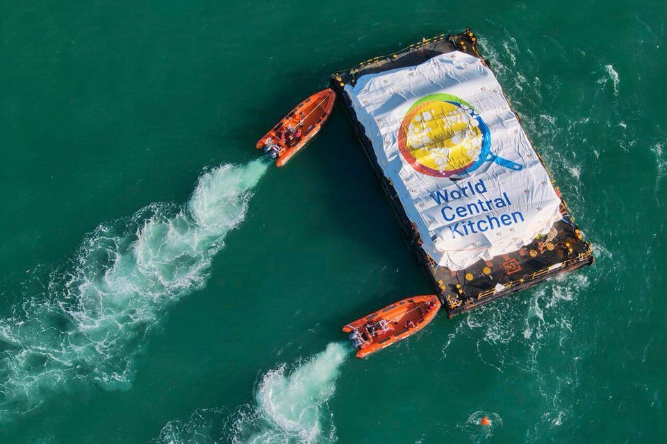 Smaller boats nudge the barge carrying 200 tonnes of food towards the shore in Gaza. Photo: IDF