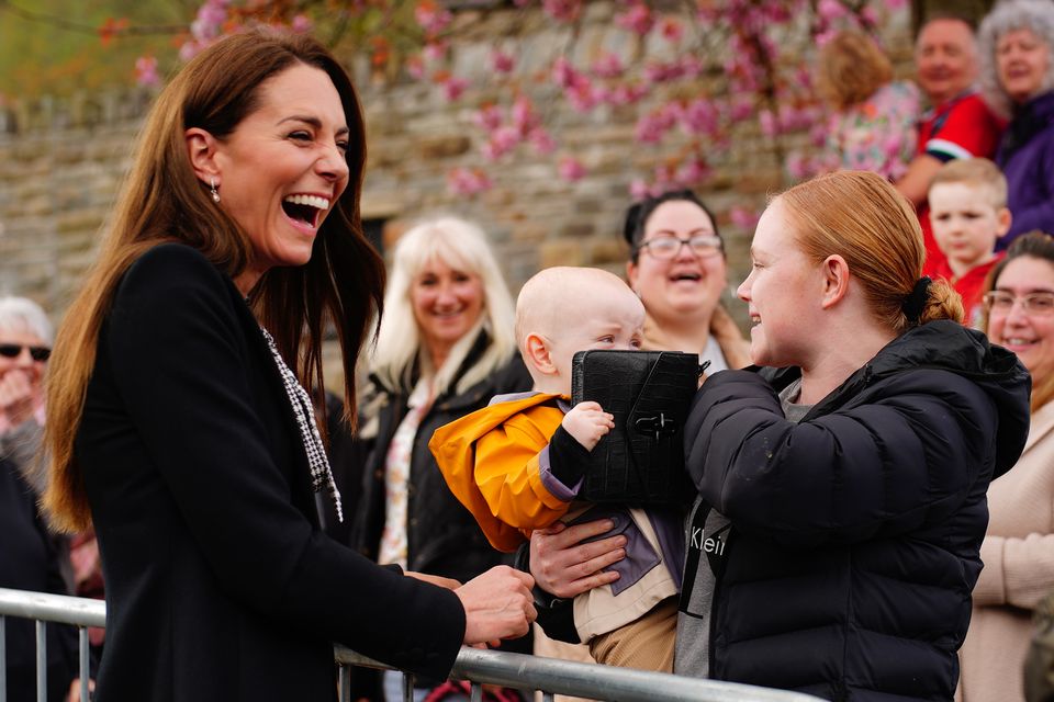 Lucy Williams, from Aberfan, holds her son Daniel Williams, one, as he takes the handbag of the Princess of Wales, during her visit with her husband the Prince of Wales, to the Aberfan Memorial Garden (Ben Birchall/PA)