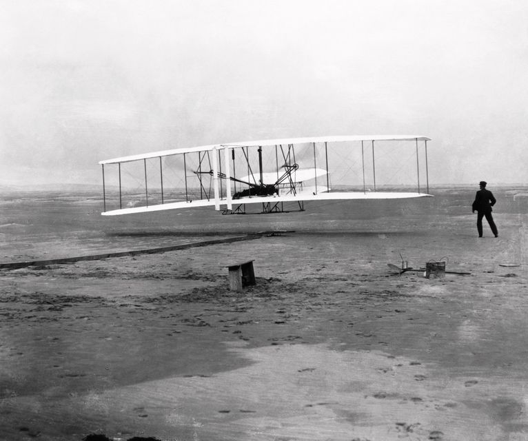 The first powered flight, made by Orville Wright on 17 December 1903 near Kill Devil Hill, Kitty Hawk, North Carolina. Wright can be seen lying on the lower wing of the 12 horse- power, chain-driven Flyer I. The flight lasted for about 12 seconds, covering a distance of 36.5 metres (120 feet) at an airspeed of 48 kilometres/ hour (30 miles/hour), a groundspeed of 10.9 kilometres/hour (6.8 miles/hour) and an altitude of 2.5-3.5 metres (8-12 feet). Photo: Getty Images/Science Photo Libra