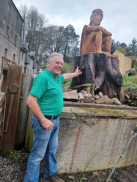 Mullichain cafe and restaurant co-owner, Martin O'Brien with the 'Mad Sweeney' wooden sculpture outside the premises in St Mullins, Co Carlow.