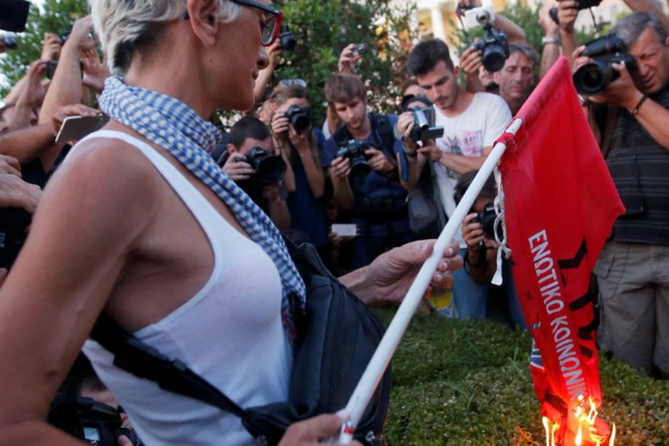 An anti-EU protester burns a leftist Syriza ruling party flag during a demonstration of about five hundred people in front of the parliament building in Athens, Greece July 13, 2015