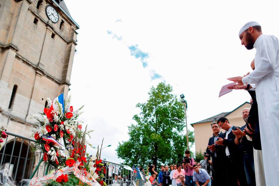 Muslims put flowers and hold a minute of silence in front of the church if Saint-Etienne-du-Rouvray, western France, where French priest Jacques Hamel was killed on July 26. Photo: AFP/Getty Images
