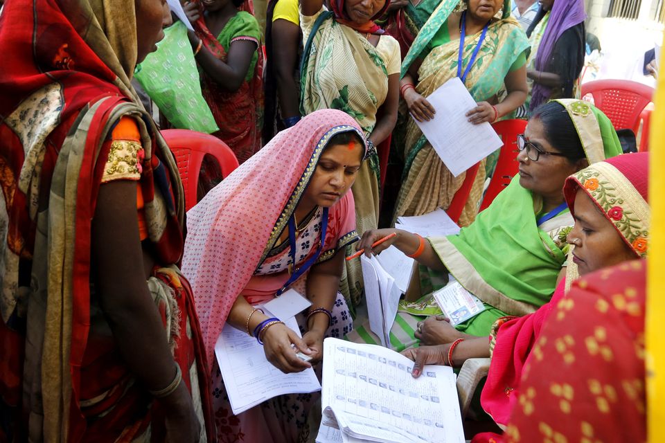 Indian women look for their names in voting list at a polling station (Rajesh Kumar Singh/AP)