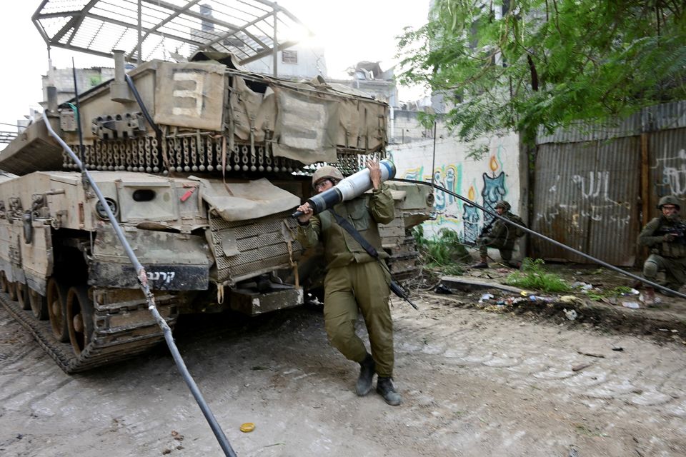 Israeli soldiers operate next to a tank at the Shajaiya district of Gaza city amid the ongoing conflict between Israel and the Palestinian Islamist group Hamas, in the Gaza Strip.