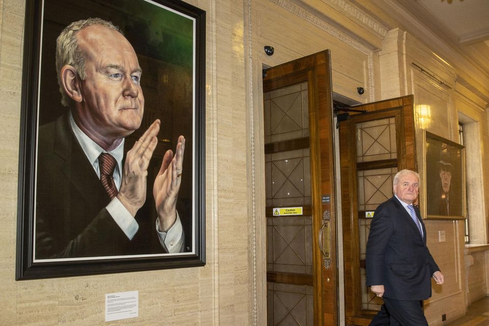 Former taoiseach Bertie Ahern passes between portraits of Martin McGuinness, left, and Ian Paisley at Stormont (PA)