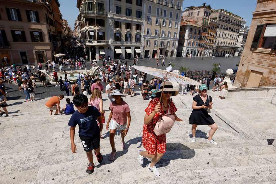 A woman shields herself from the sun with an umbrella at the Spanish Steps, Rome, as a heat wave blanketed Italy yesterday. Photo: Reuters/Remo Casilli