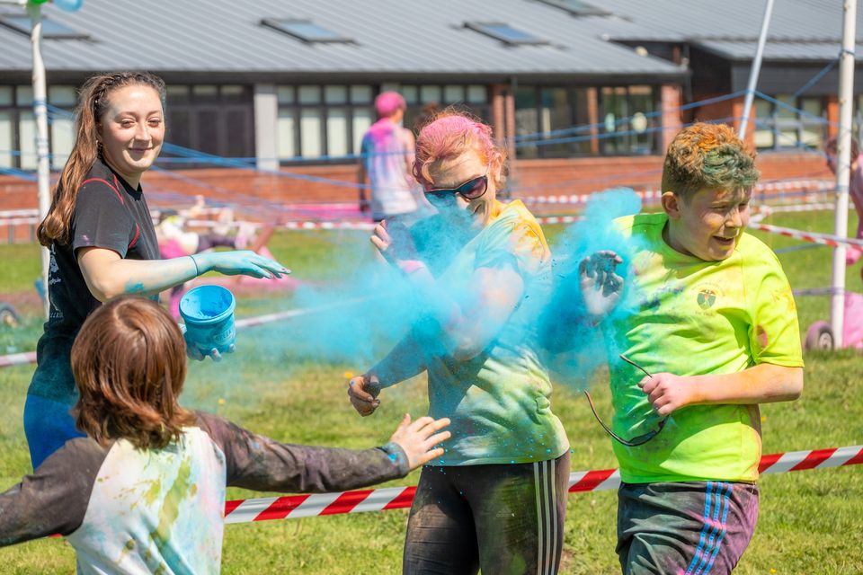 Bethany Hastie throws some coloured powder on Lisa McGettigan and Sam Nolan at the East Glendalough School Colour Run. Photo: Leigh Anderson