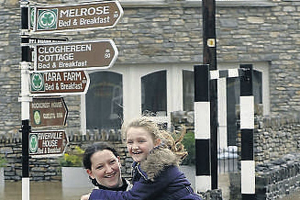 Emer and Niamh Finnegan wade through flooded streets in Kenmare on their way home