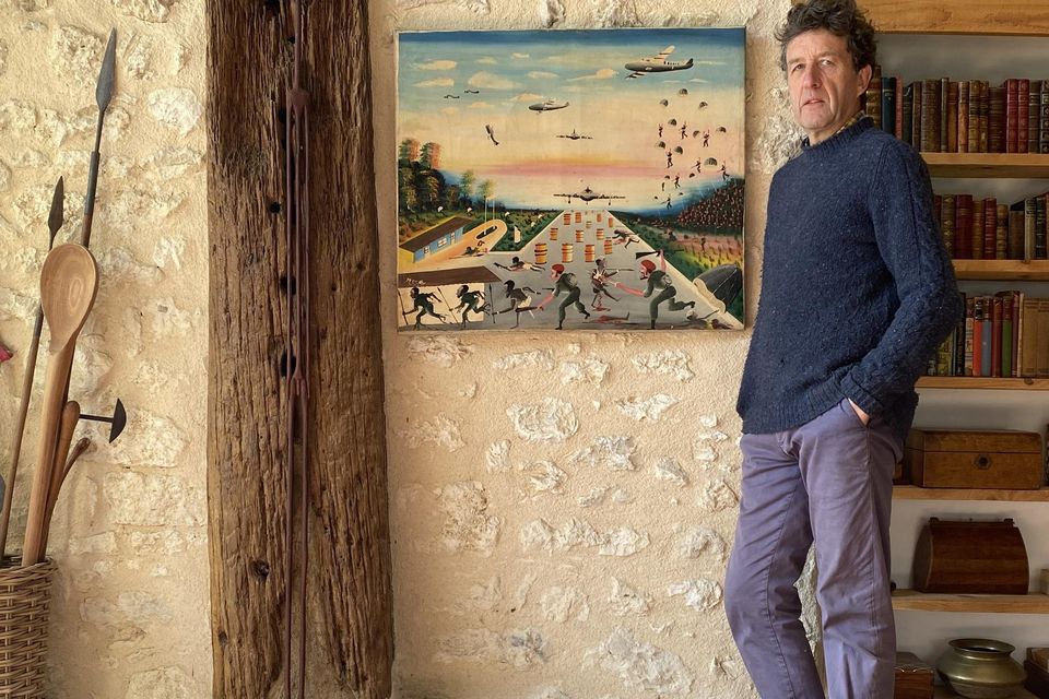 David Orr standing beside his African painting at home in France