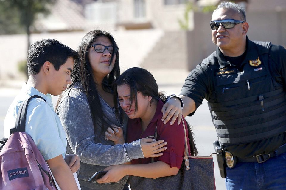 A policeman comforts pupils after the shooting at Independence High School in Glendale (AP)