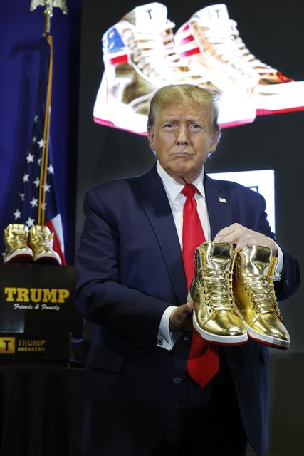 US President Donald Trump holding a pair of gold 'Never Surrender' high tops. Photo: Getty