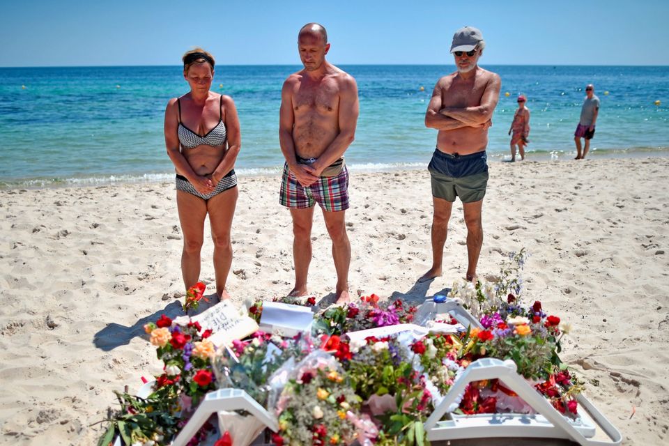 Holidaymakers view flowers left on Marhaba beach where 38 people were killed in a terrorist attack in June 2015 in Sousse, Tunisia