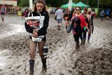 thumbnail: Festivalgoers make their way through the mud
