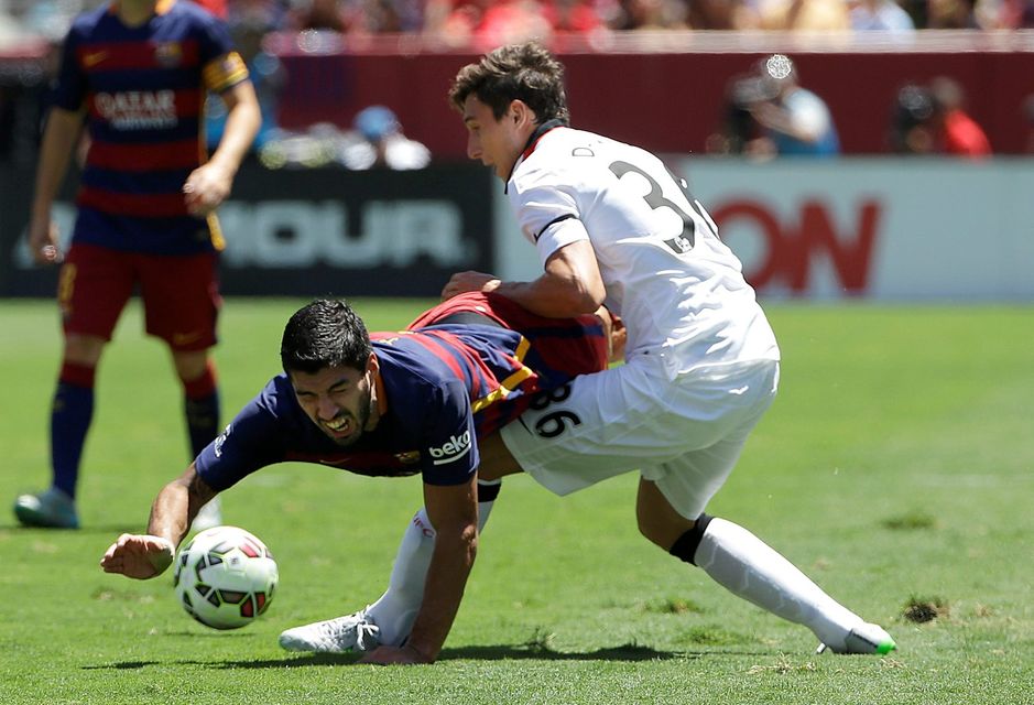 FC Barcelona's Luis Suarez, left, falls next to Manchester United's Matteo Darmian during the first half of an International Champions Cup soccer match in Santa Clara, Calif., Saturday, July 25, 2015. (AP Photo/Jeff Chiu)