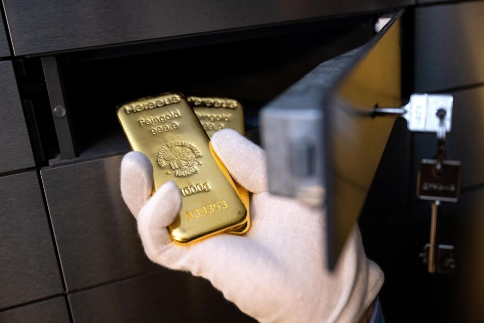 Stock image: A man places two gold bars in a locker in a vault. Photo: Sven Hoppe via Getty Images.