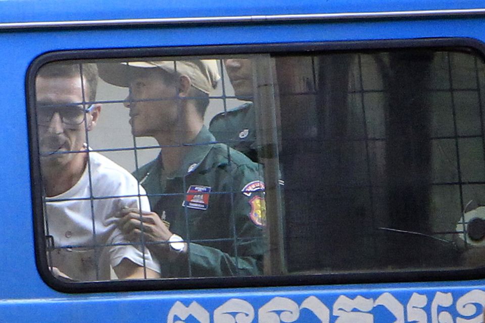 Daniel Jones, left, is escorted by a prison guard to a waiting van outside the Siem Reap court (AP Photo/Heng Sinith)