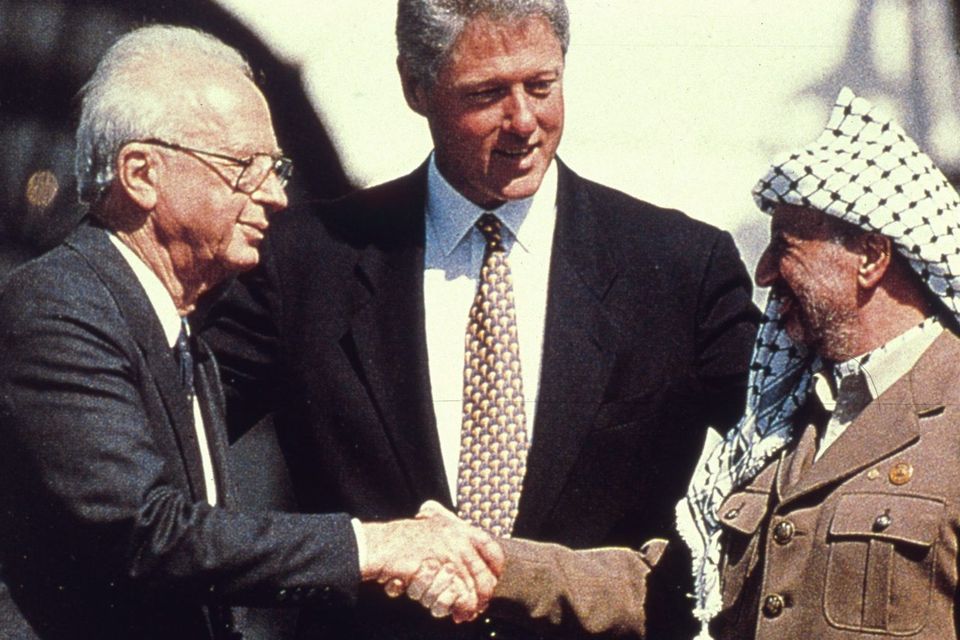 Bill Clinton watches as the Israeli Prime Minister Yitzhak Rabin shakes hands with the Palestinian leader Yasser Arafat in the garden of the White House after the signing of the deal transferring much of the West Bank to Palestinian control