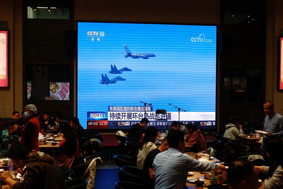 Beijing restaurant customers next to a giant screen broadcasting footage of Chinese air force jets taking part in exercises around Taiwan yesterday. Photo: Tingshu Wang/Reuters