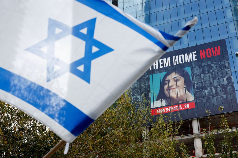 An Israeli flag flutters near a billboard with pictures of hostages kidnapped in the deadly October 7 attack on Israel by the Palestinian Islamist group Hamas from Gaza, in Tel Aviv, Israel March 18, 2024. REUTERS/Carlos Garcia Rawlins