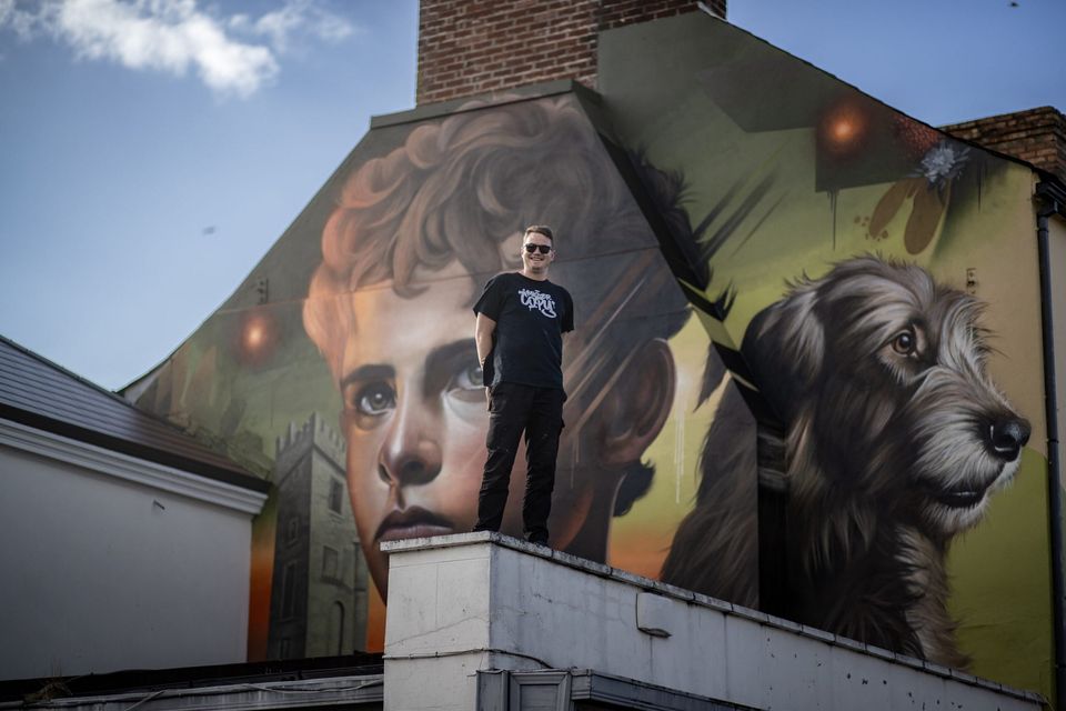 Artist Mister Copy, who is returning to the 2024 SEEK Urban Arts Festival, pictured with the mural of Setanta that he painted last year. Photo: Mister Copy
