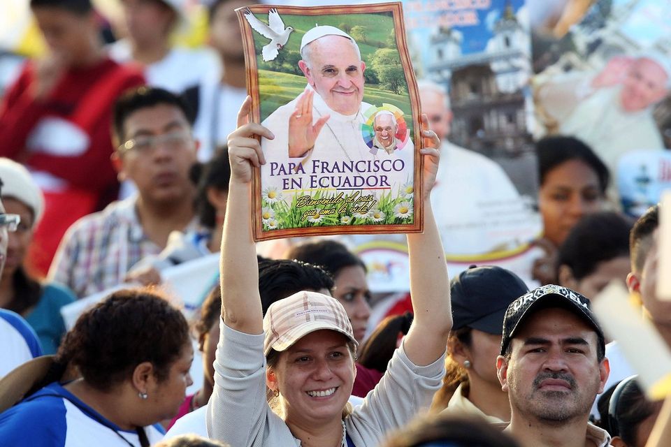 A woman holds up a poster of Pope Francis in a crowd of thousands at Samanes Park in Guayaquil, Ecuador (AP)