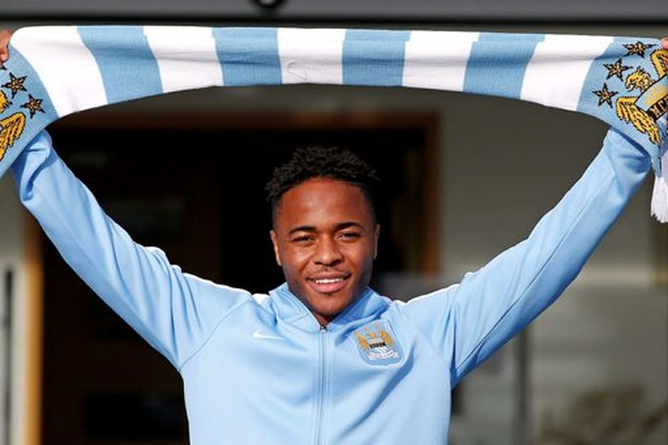 New Manchester City signing Raheem Sterling poses with a club scarf as he leaves the club's Etihad Stadium in Manchester