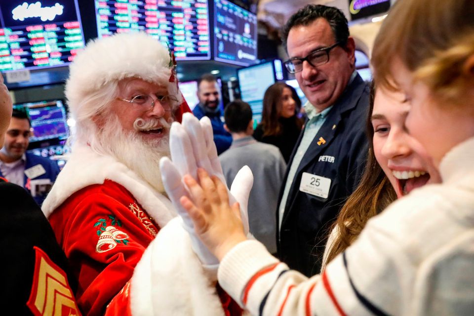 Hudson Maloney, son to specialist trader Gregg Maloney, is given a high five by Santa Claus, on the floor during the traditional bring-your-kids-to-work day at the New York Stock Exchange (NYSE)