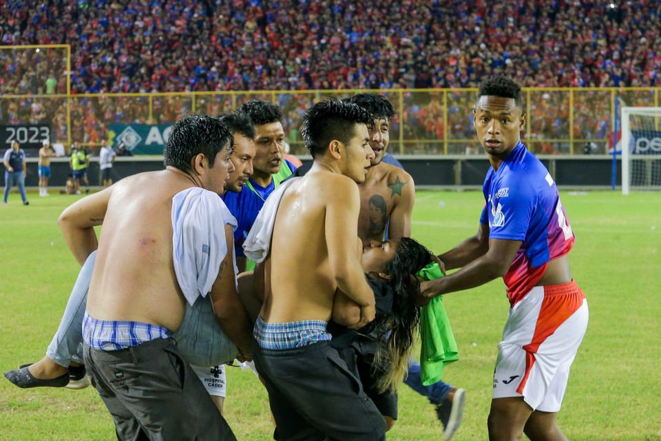 Spectators and a player carry an injured fan on to the field of Cuscatlan stadium in El Salvador. Photo: Milton Flores/AP