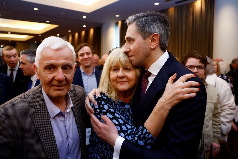 Taoiseach-elect Simon Harris embraces his mother Mary, alongside his father Bart, after being announced as the new leader of Fine Gael in Athlone yesterday. Photo: Reuters/Clodagh Kilcoyne