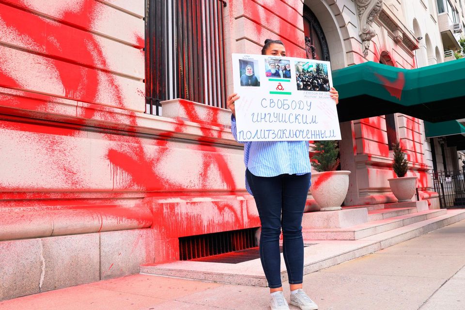 A woman holds a protest sign as she stands in front of a vandalised Russian Consulate in New York City. Getty
