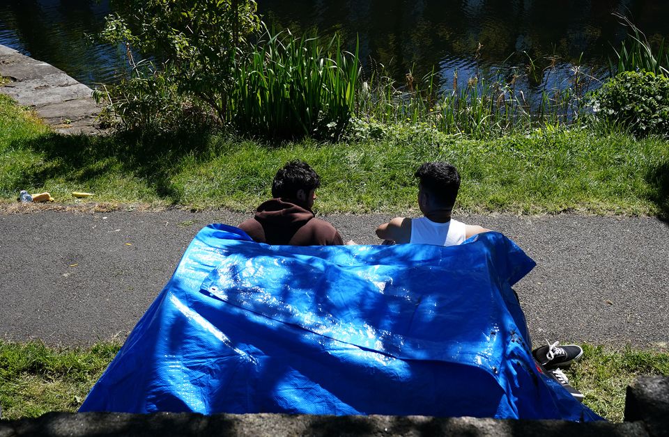 Two people sit outside one of the dozens of tents (Brian Lawless/PA)