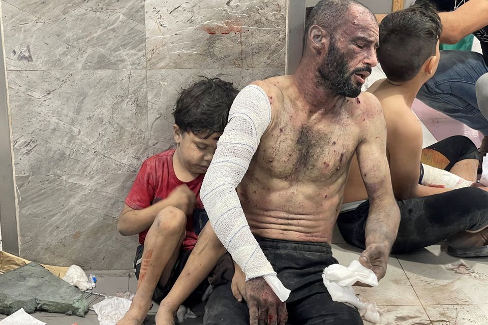 A Palestinian man and his son, who were wounded in an Israeli strike, sit on the floor at Al-Shifa Hospital in Gaza City, yesterday. Photo: Reuters