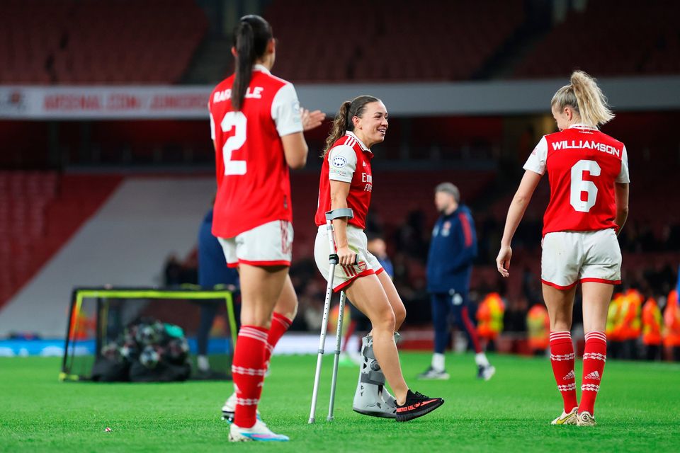 Katie McCabe of Arsenal, seen with crutches after picking up an injury in the game, speaks with team-mate Leah Williamson