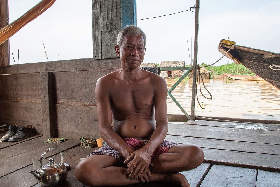 A former fisherman poses in his home at the floating village of Mechrey