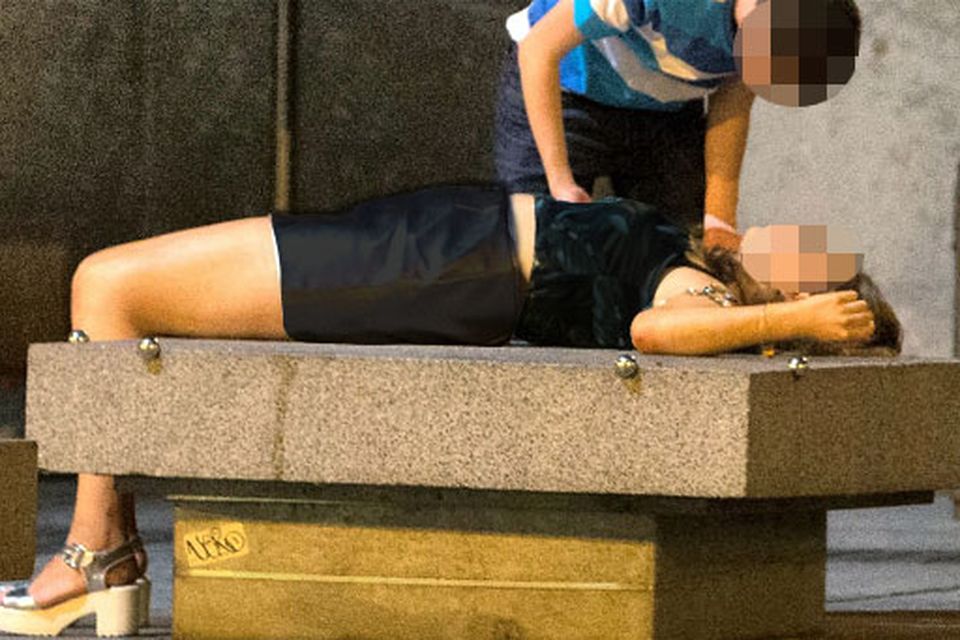 A teenage girl in a collapsed state being tended to by a friend outside the central bank