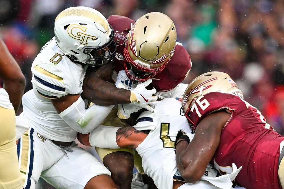 24 August 2024; Florida State Seminoles running back Roydell Williams is tackled by linebacker Trenilyas Tatum, left, and Georgia Tech Yellow Jackets linebacker Kyle Efford during the 2024 Aer Lingus College Football Classic match between Florida State and Georgia Tech at Aviva Stadium in Dublin. Photo by Brendan Moran/Sportsfile 