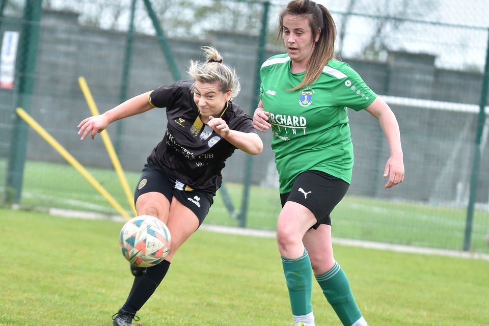 Carnew FC's Nicole Curran gets her shot away as Edwina Sayer closes in. 
