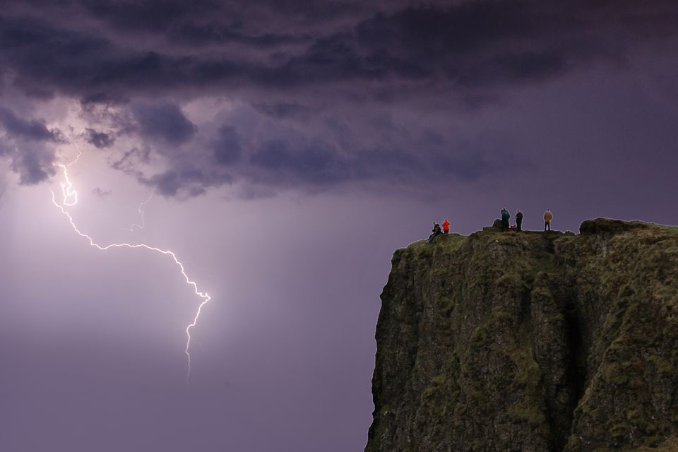 Walkers take in the spectacular view of a thunderstorm at the top of Cave Hill