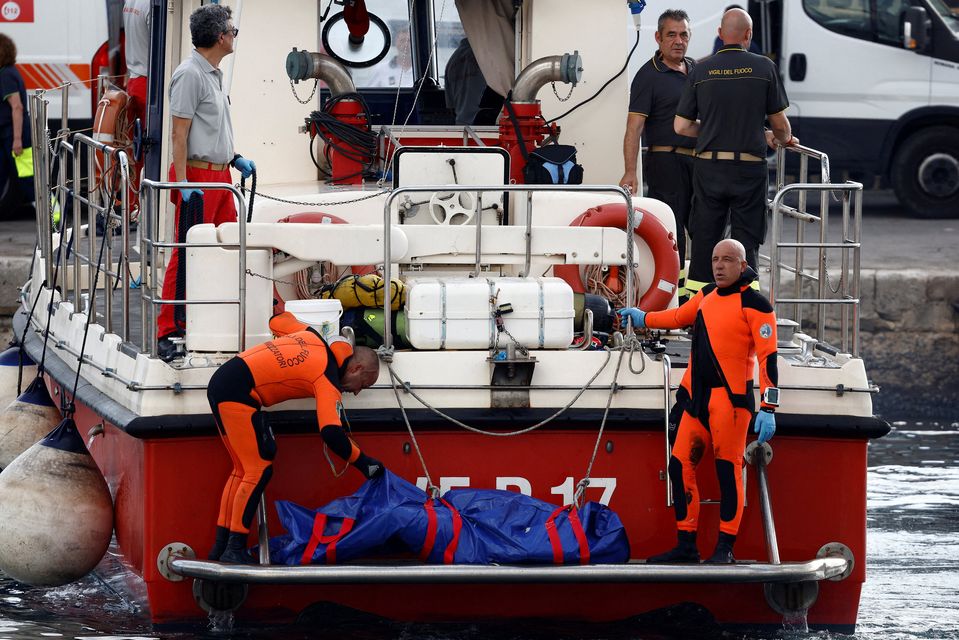 Rescue workers with a body bag containing the remains of tech tycoon Mike Lynch, who was born in Britain to Irish parents, in the port of Porticello. Photo: Reuters