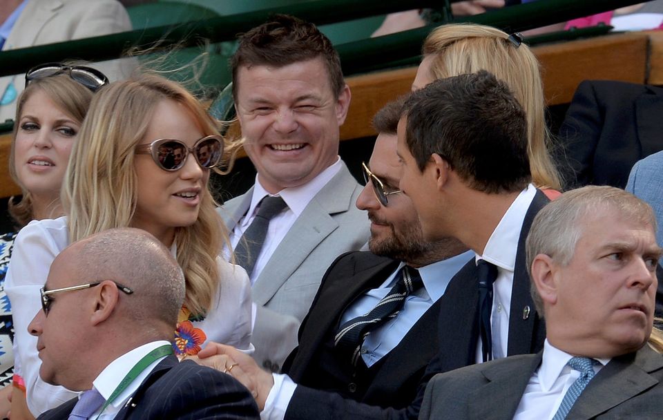 Rugby player Brian O'Driscoll (C), model Suki Waterhouse (L), actor Bradley Cooper (CENTRE 2nd R) and television presenter Bear Grylls (CENTRE R) sit on Centre Court at the Wimbledon Tennis Championships