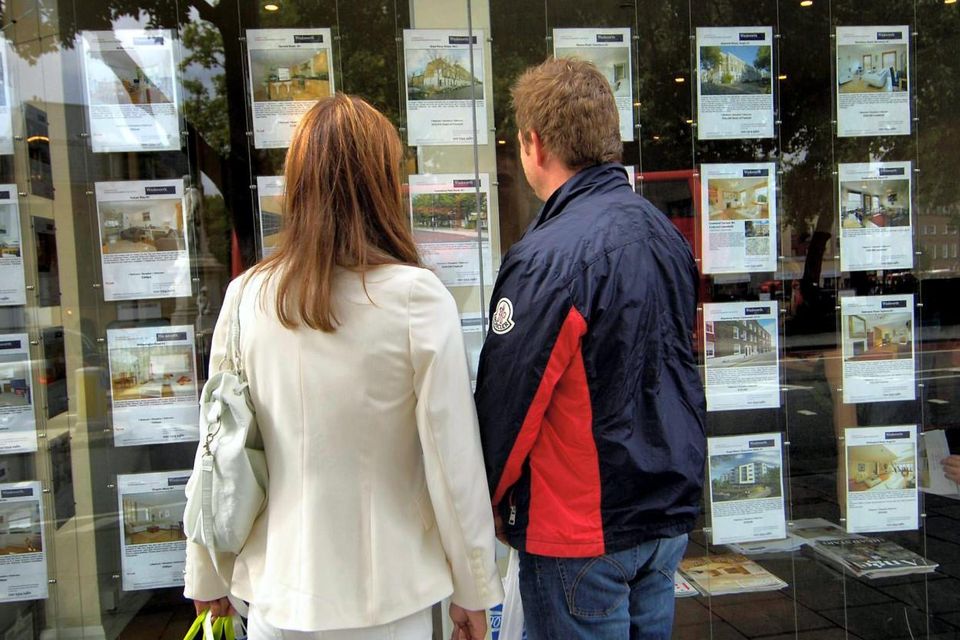 A couple look at their options outside an estate agent's window