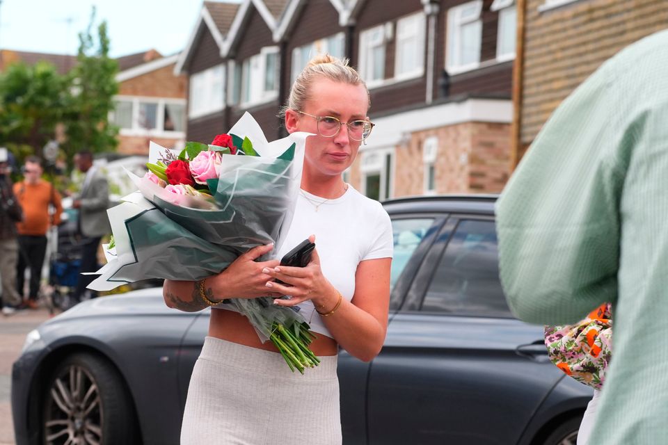 A woman delivers floral tributes near to the scene in Bushey, Hertfordshire. Photo: PA