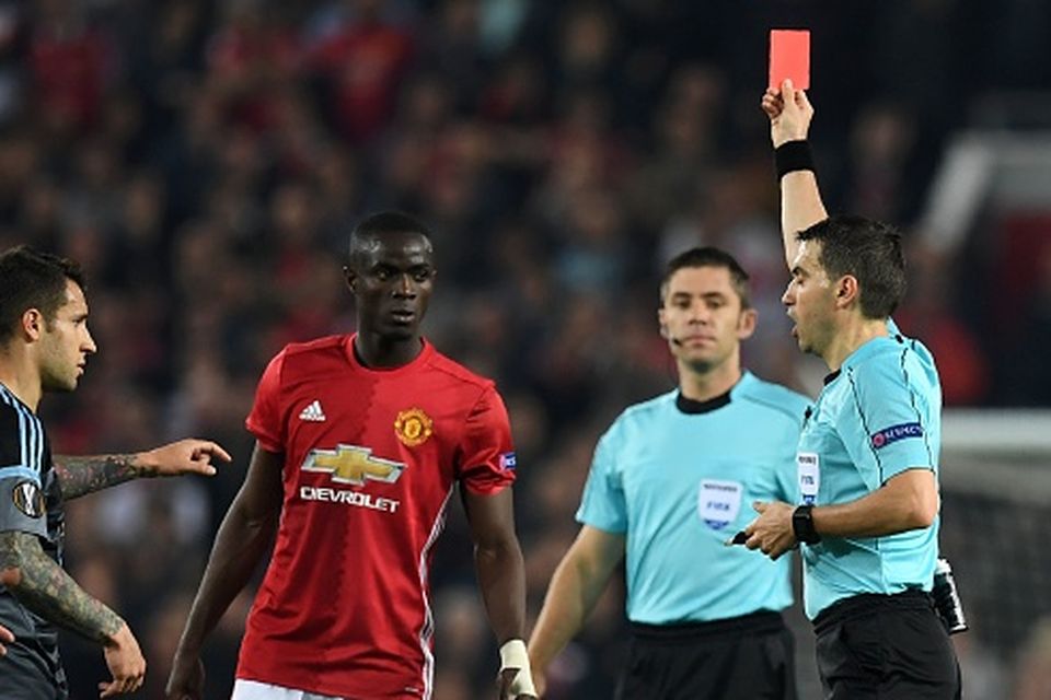 Romanian referee Ovidiu Hategan (R) shows a red card to Manchester United's Ivorian defender Eric Bailly (C), after a clash between players during the UEFA Europa League semi-final, second-leg football match between Manchester United and Celta Vigo at Old Trafford stadium in Manchester, north-west England, on May 11, 2017. / AFP PHOTO / Paul ELLIS
