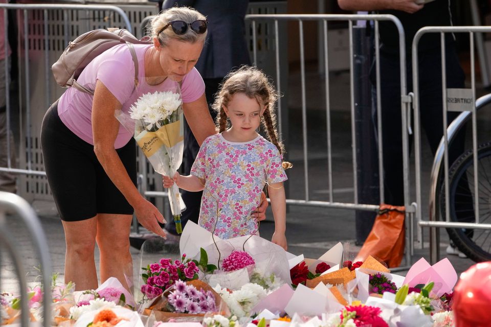 A girl and a woman place flowers as a tribute near a crime scene at Bondi Junction in Sydney